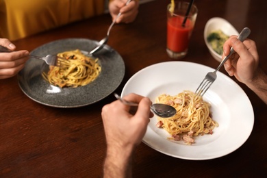 Lovely young couple having pasta carbonara for dinner at restaurant, closeup view