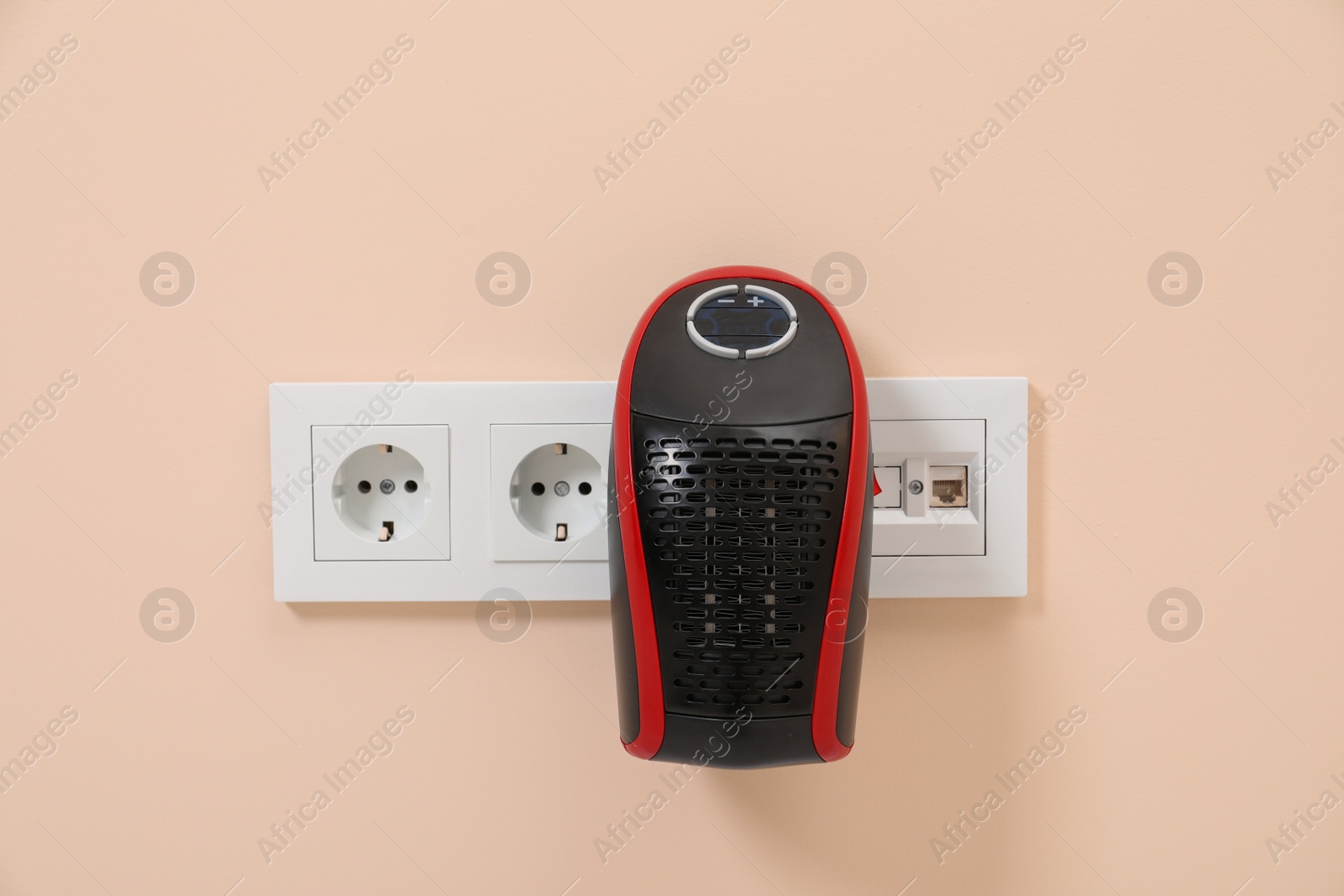 Photo of Modern compact electric heater charging from socket indoors