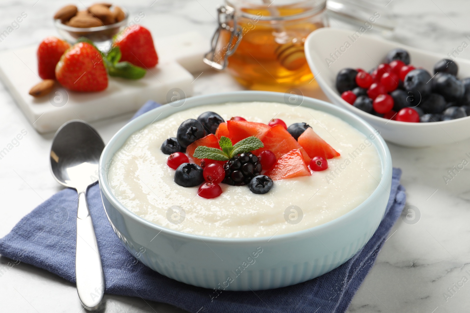 Photo of Delicious semolina pudding with berries on white marble table