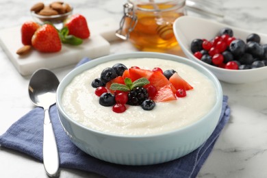 Photo of Delicious semolina pudding with berries on white marble table