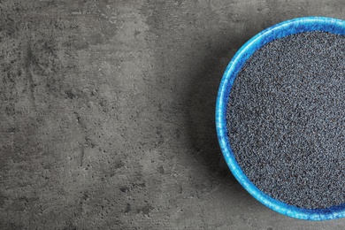 Poppy seeds in bowl and space for text on grey background, top view