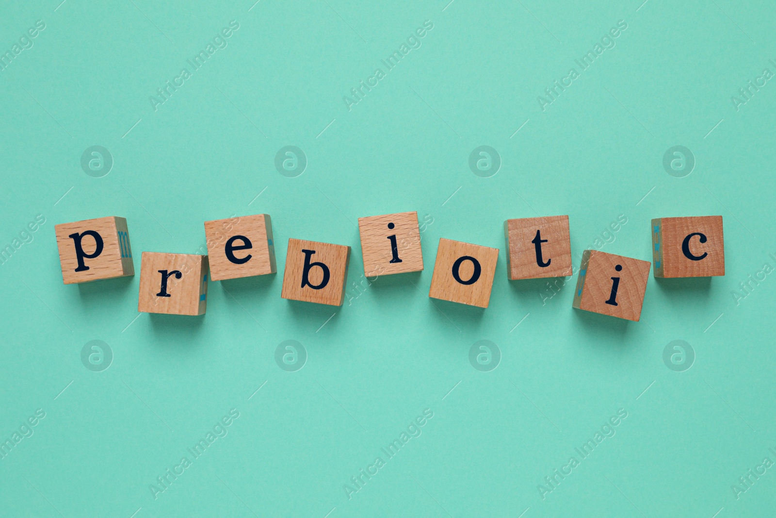 Photo of Wooden cubes with word Prebiotic on turquoise background, flat lay