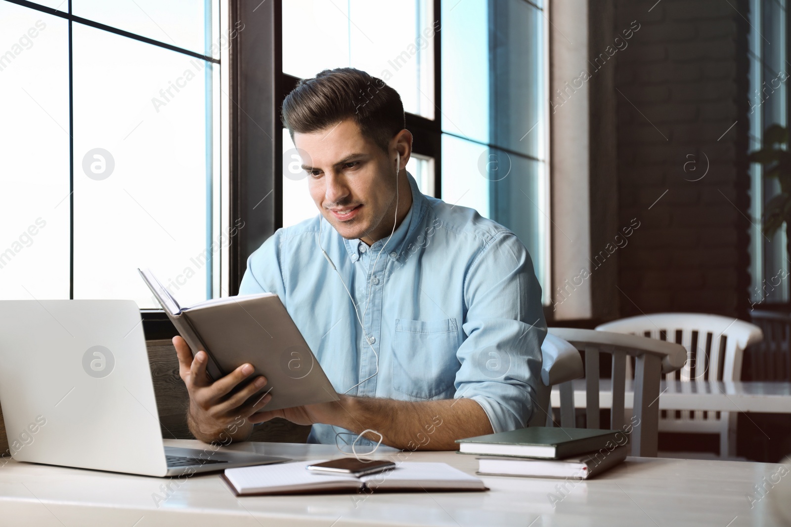 Photo of Man listening to audiobook at table in cafe