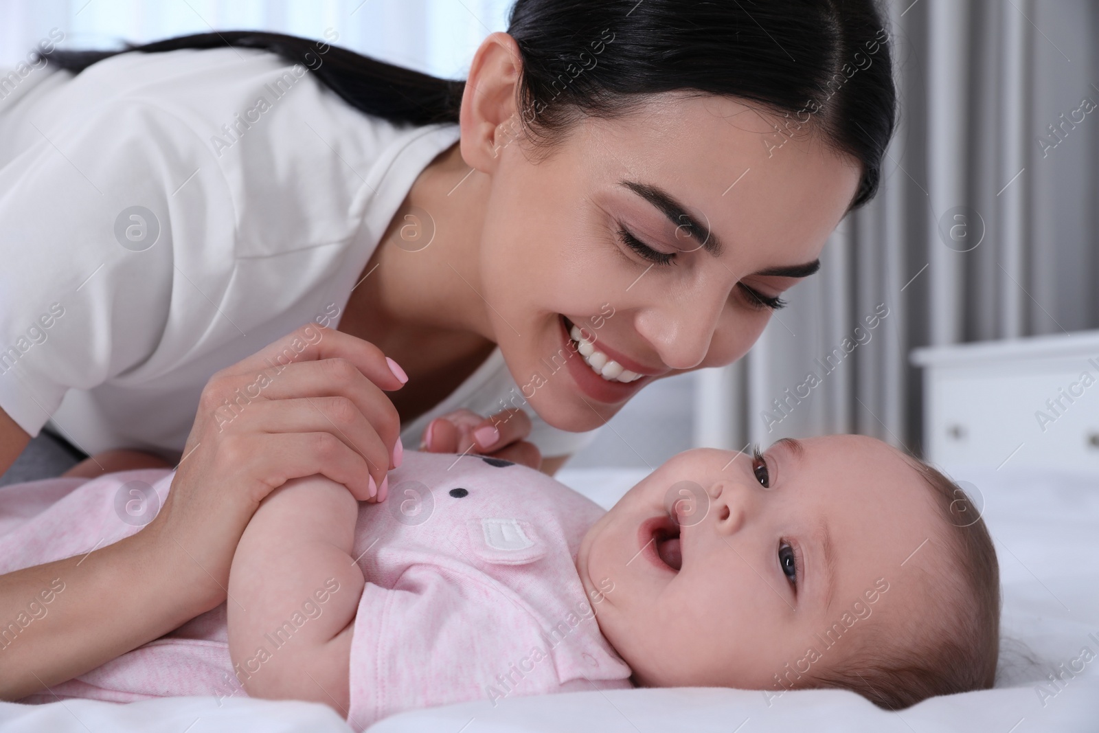 Photo of Young mother with her little baby on bed at home