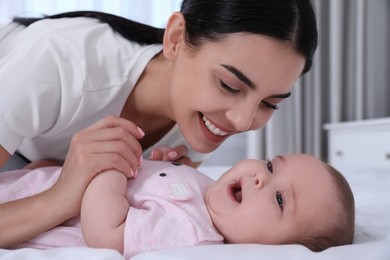 Young mother with her little baby on bed at home