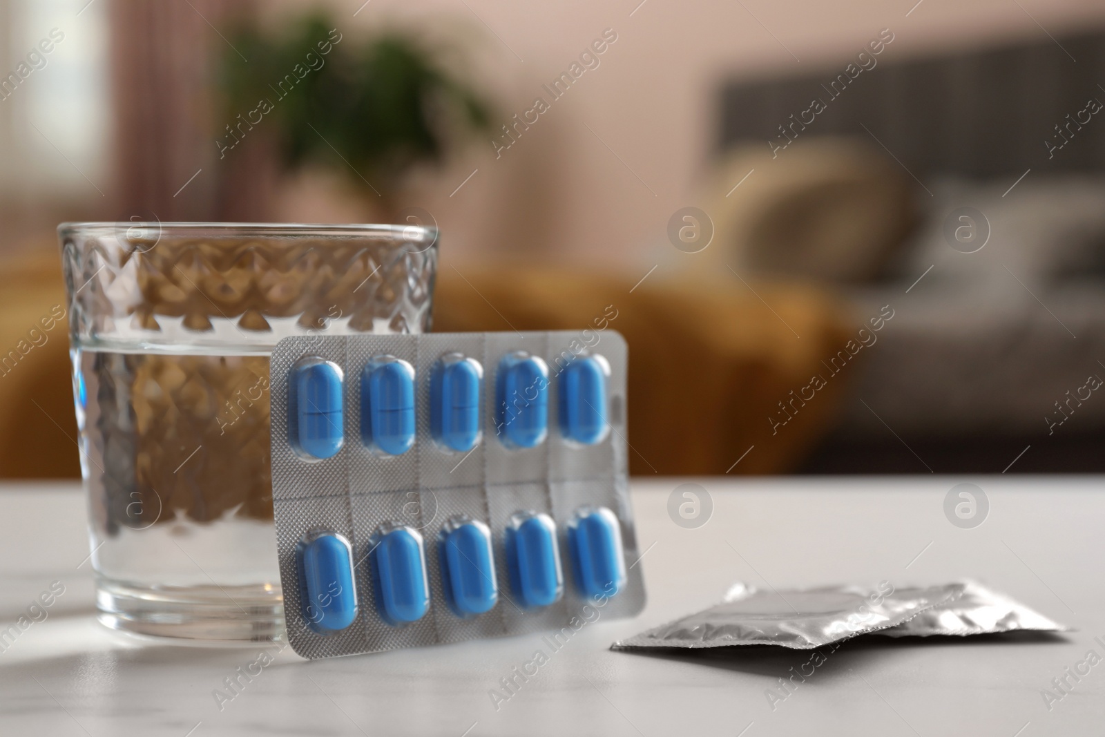 Photo of Glass of water, condoms and pills on white table indoors, closeup with space for text. Potency problem concept