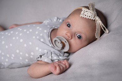 Photo of Adorable newborn baby with pacifier on bed