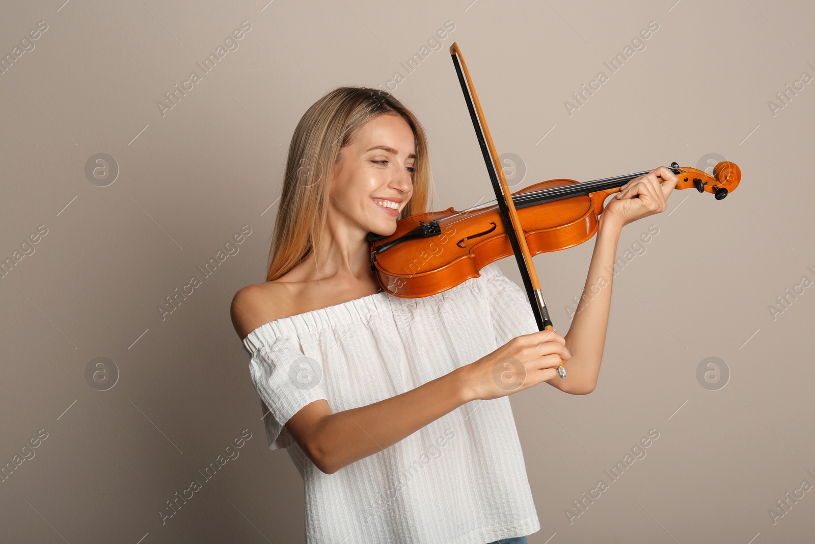 Photo of Beautiful woman playing violin on beige background