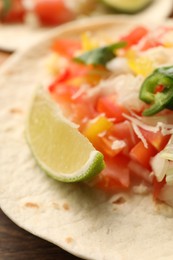 Photo of Delicious taco with vegetables and lime on table, closeup