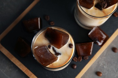 Glasses of milk with coffee ice cubes on grey table, top view
