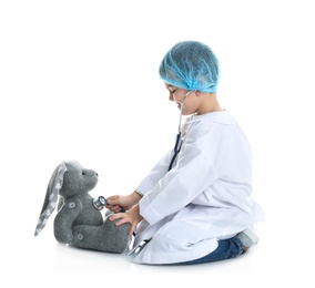 Cute child playing doctor with stuffed toy on white background