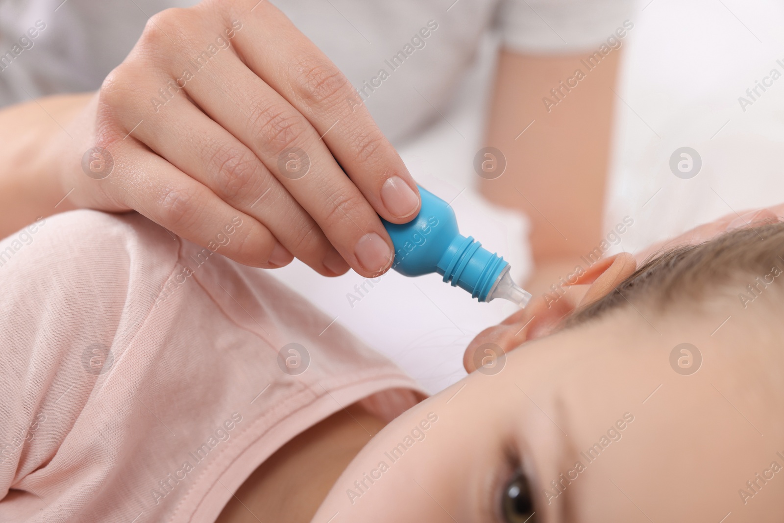 Photo of Mother dripping medication into daughter's ear, closeup