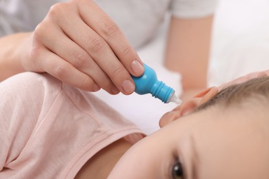 Mother dripping medication into daughter's ear, closeup