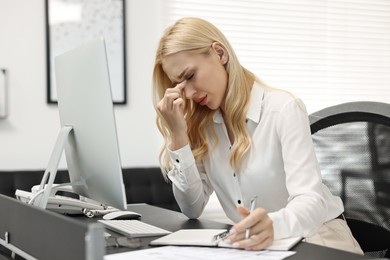 Photo of Overwhelmed woman with pen at table in office