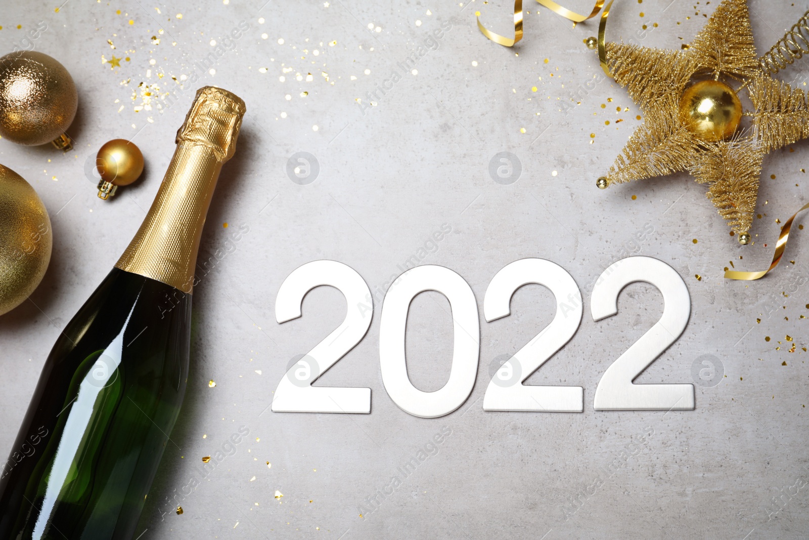 Photo of Happy New Year 2022! Flat lay composition with bottle of sparkling wine on light grey table