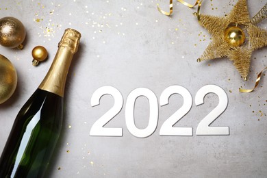 Happy New Year 2022! Flat lay composition with bottle of sparkling wine on light grey table