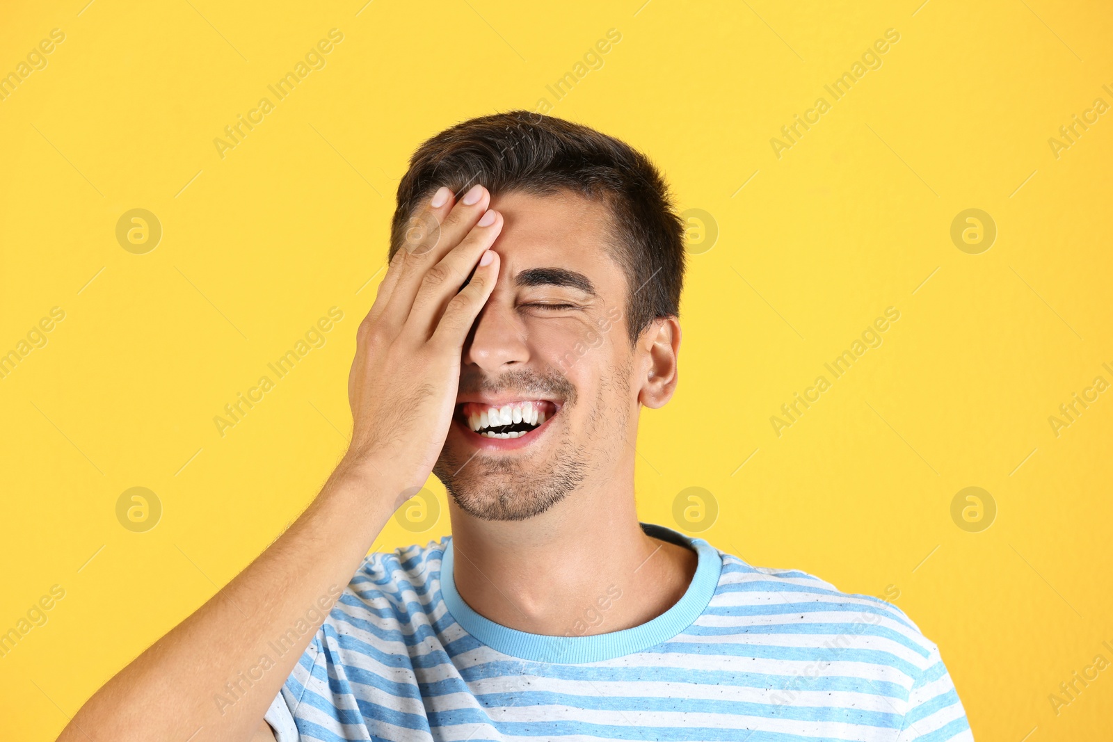 Photo of Portrait of handsome young man laughing on color background