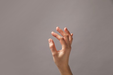 Photo of Woman holding something in hand on grey background, closeup. Space for text