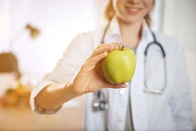 Image of Nutritionist with fresh apple in her office, closeup