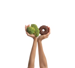 Photo of Woman choosing between doughnut and fresh broccoli on white background, closeup