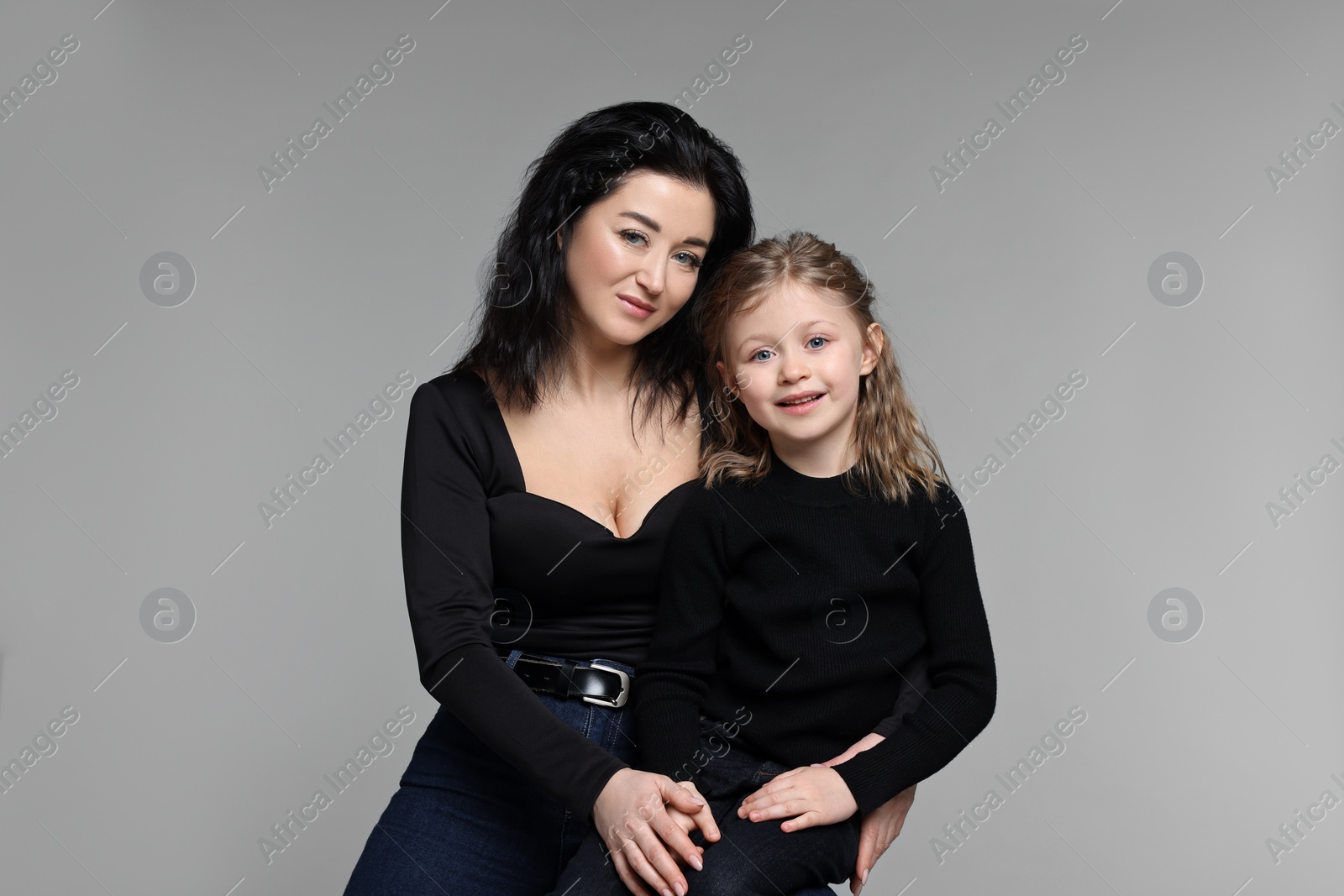 Photo of Beautiful mother with little daughter on grey background