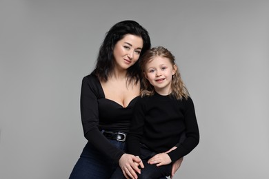 Beautiful mother with little daughter on grey background