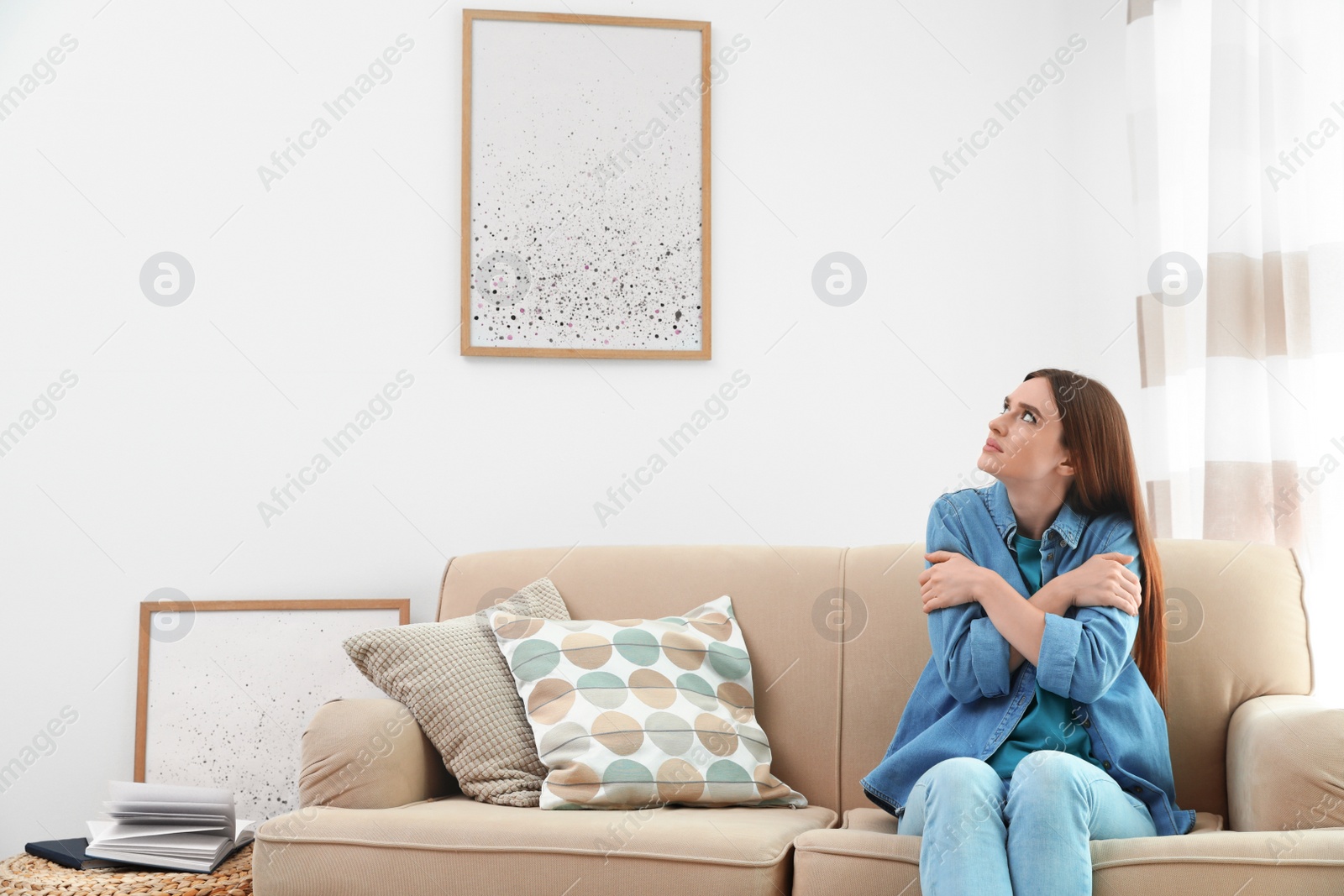 Photo of Young woman freezing under air conditioner at home