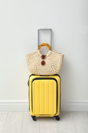 Photo of Suitcase packed for trip and summer accessories near white wall indoors