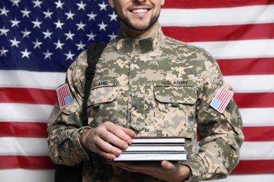 Cadet with backpack and books against American flag, closeup. Military education