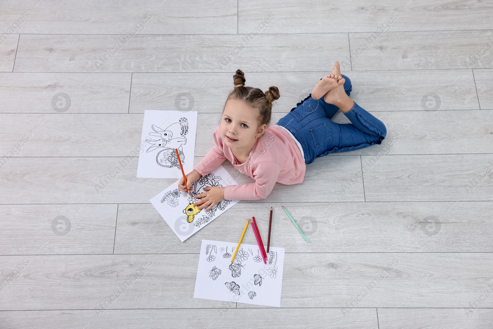 Photo of Cute little girl coloring on warm floor indoors. Heating system