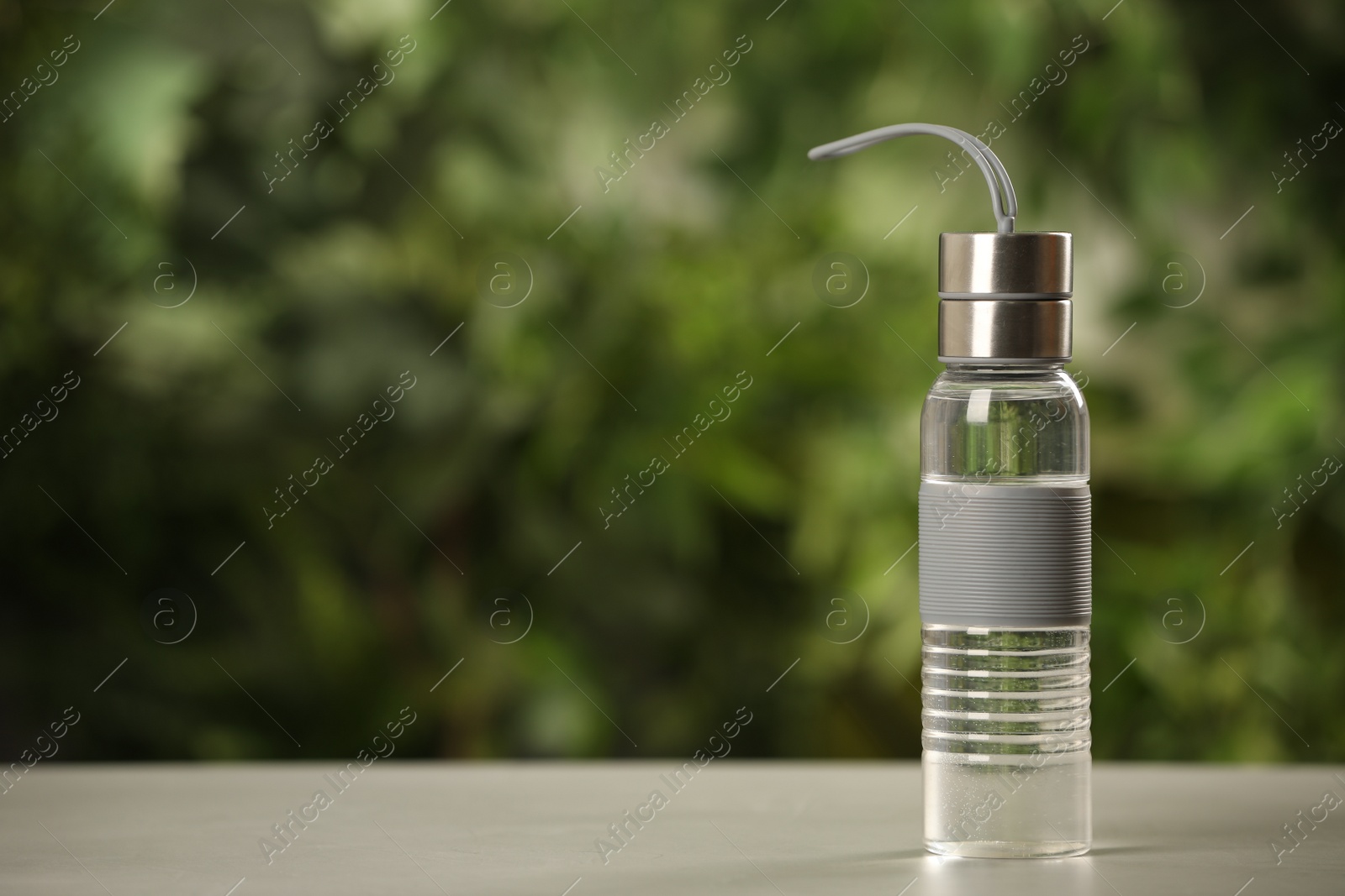 Photo of Sport bottle of water on white wooden table outdoors, space for text