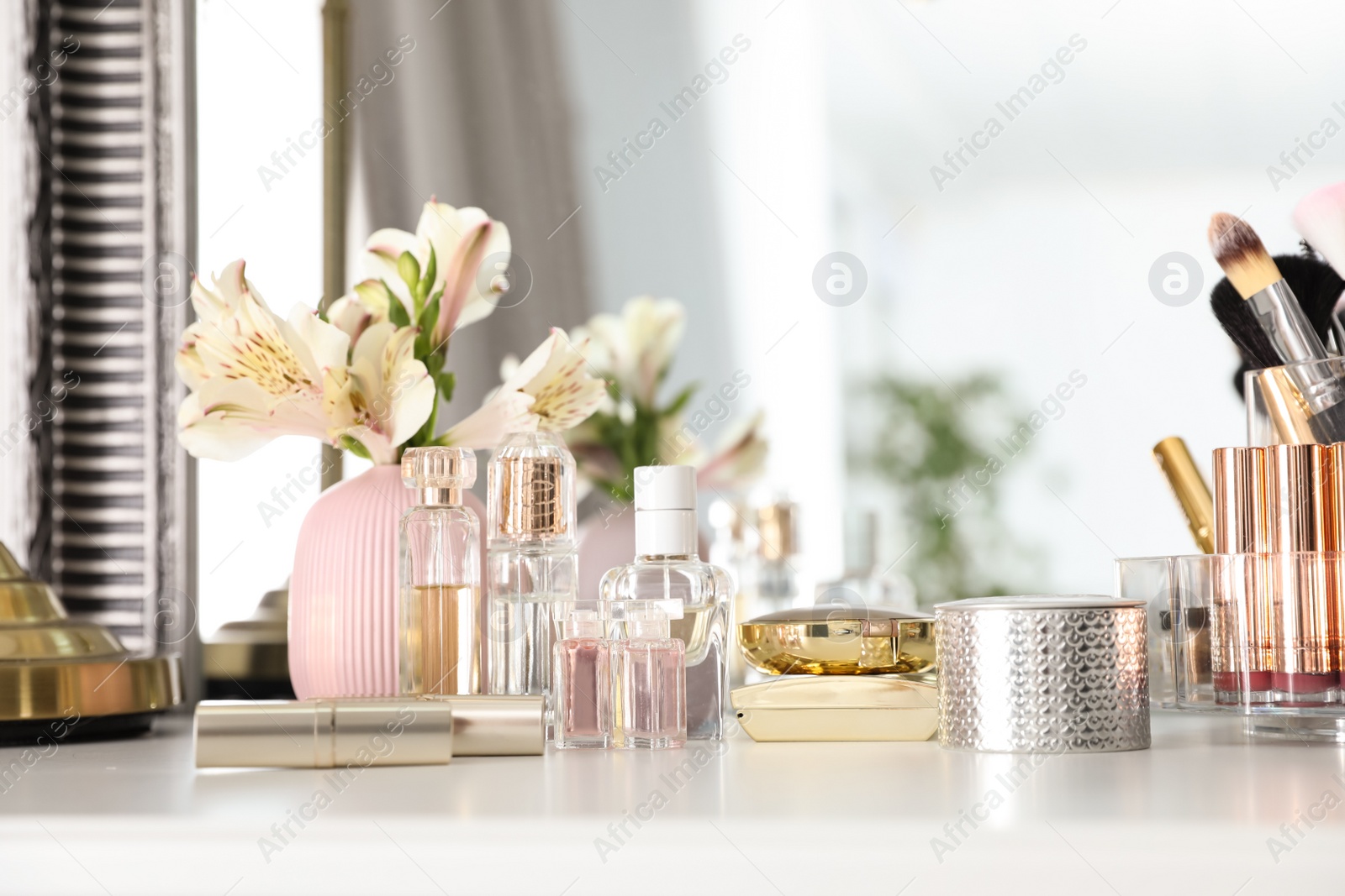 Photo of Luxury makeup products and accessories with perfumes on dressing table