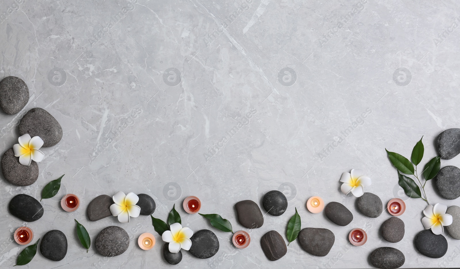 Photo of Flat lay composition with spa stones and lit candles on grey marble background, space for text