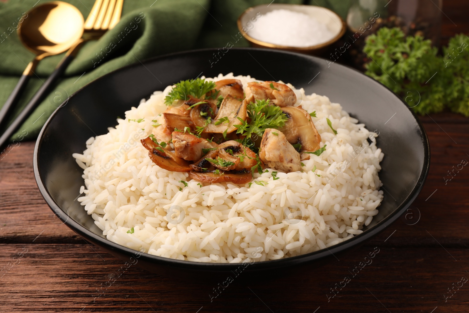 Photo of Delicious rice with mushrooms and parsley on wooden table, closeup