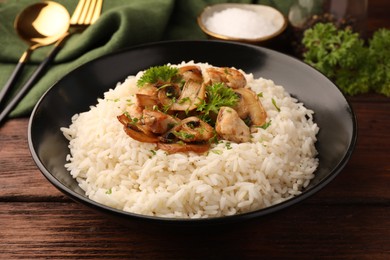 Photo of Delicious rice with mushrooms and parsley on wooden table, closeup