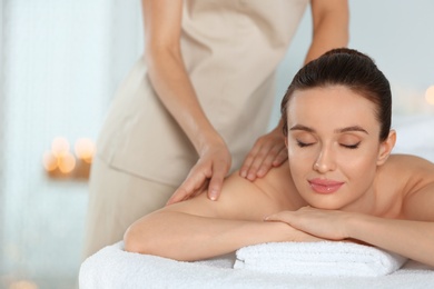 Photo of Beautiful young woman enjoying massage in spa salon