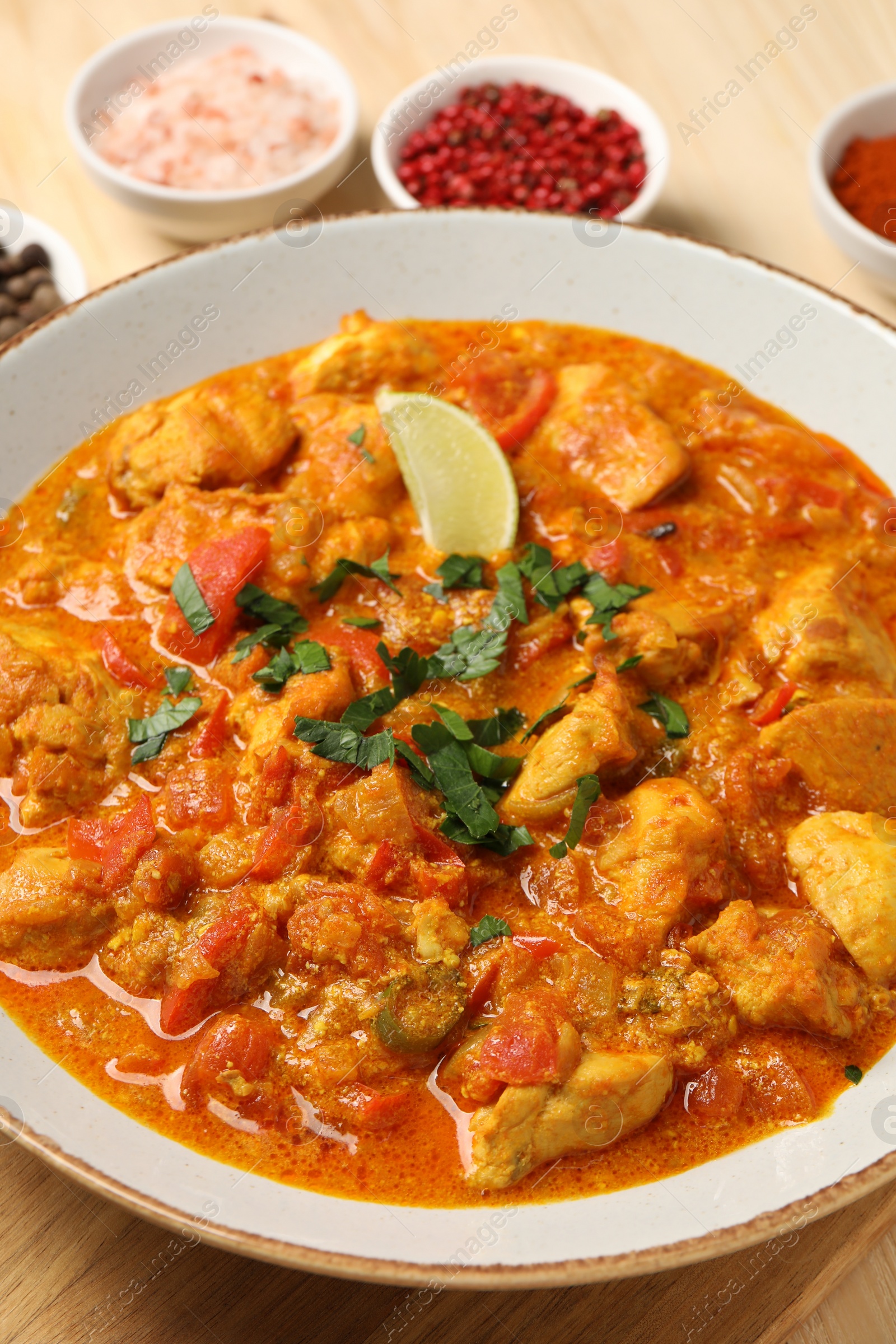 Photo of Delicious chicken curry and spices on table