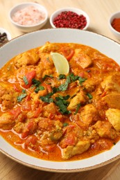 Delicious chicken curry and spices on table