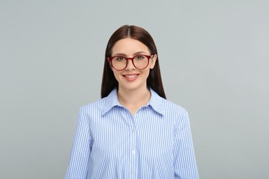 Portrait of smiling woman in stylish eyeglasses on grey background