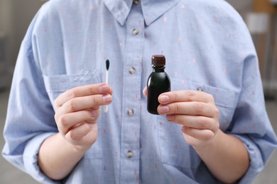 Photo of Woman holding bottle of brilliant green and cotton bud, closeup