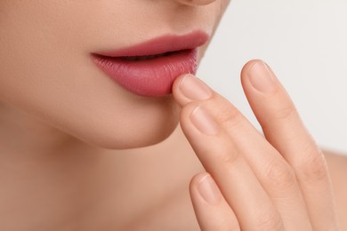 Young woman with beautiful full lips on white background, closeup