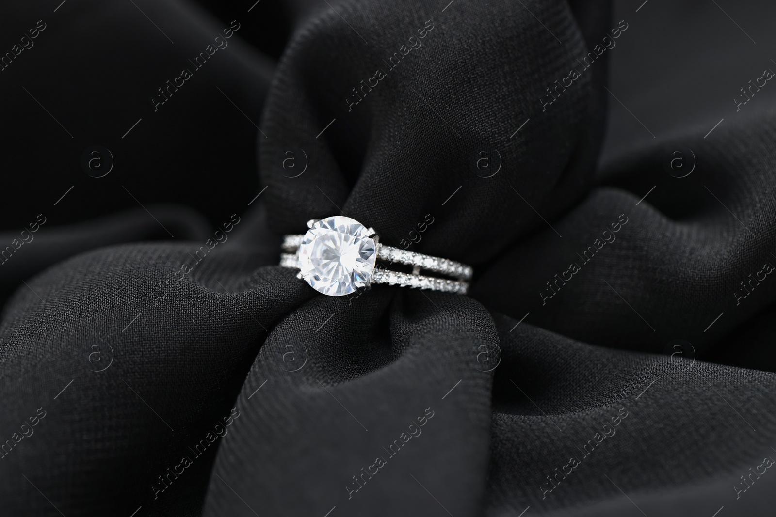 Photo of Beautiful ring with gemstones on black fabric. Luxury jewelry