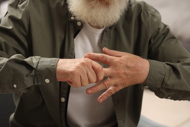 Photo of Senior man suffering from pain in hand on blurred background, closeup. Rheumatism symptom