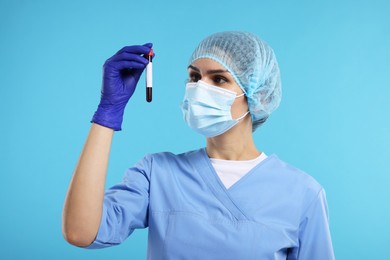 Photo of Laboratory testing. Doctor with blood sample in tube on light blue background