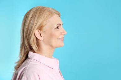 Portrait of mature woman with beautiful face on blue background. Space for text