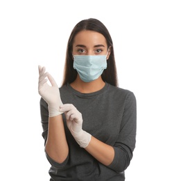 Woman in protective face mask putting on medical gloves against white background