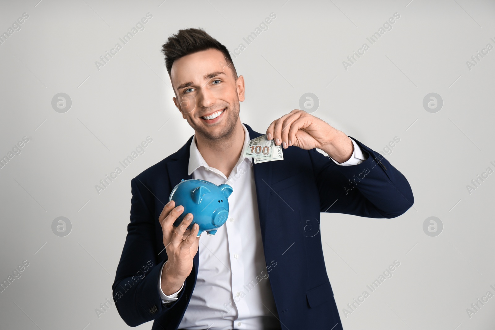 Photo of Happy man with cash money and piggybank on light grey background