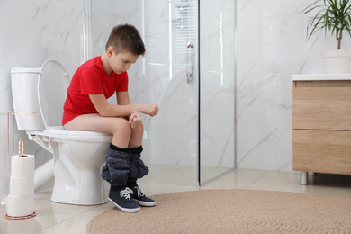 Boy suffering from hemorrhoid on toilet bowl in rest room