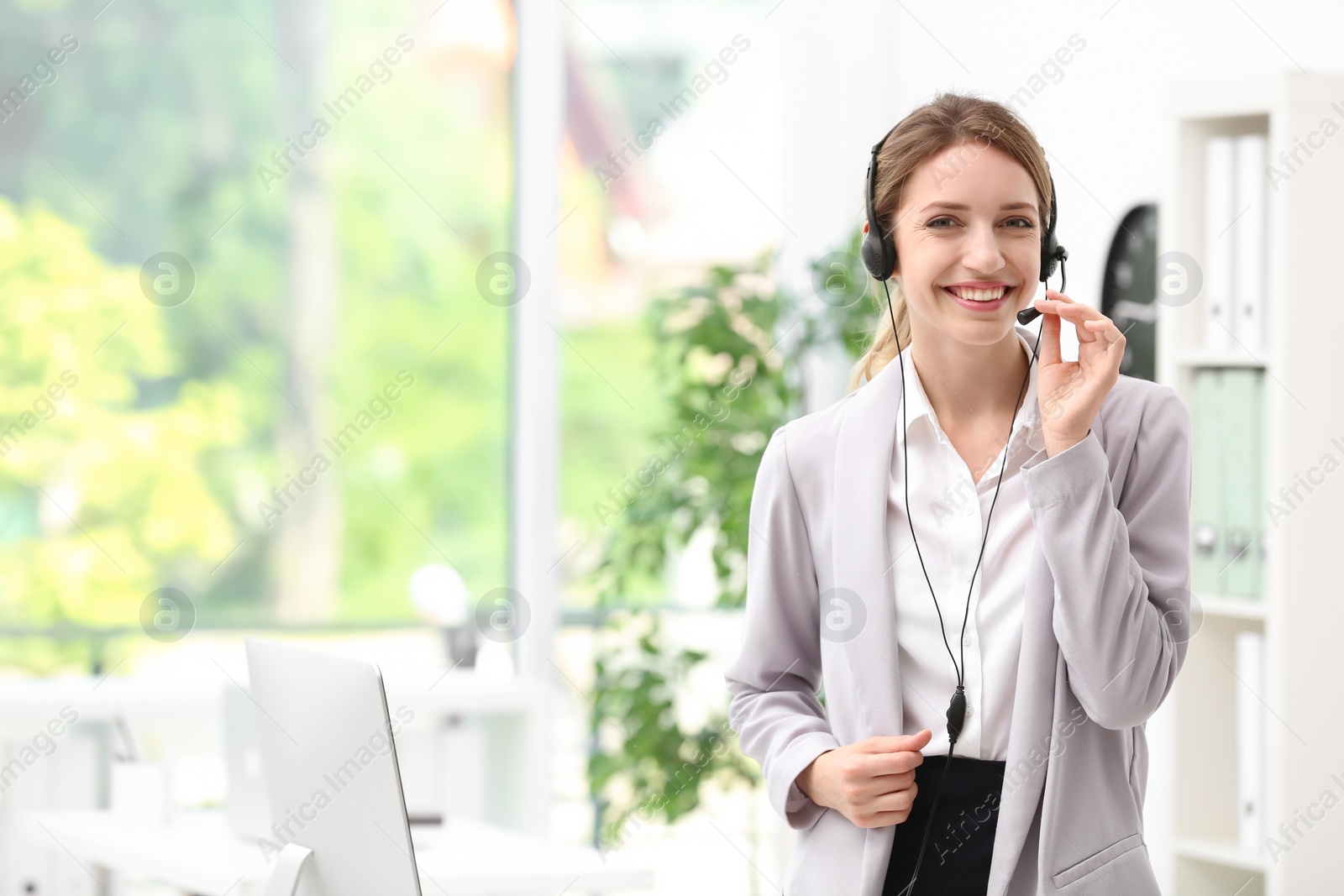 Photo of Young female receptionist with headset in office