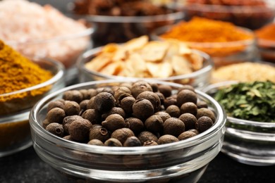 Photo of Glass bowls with different spices on grey textured table, closeup